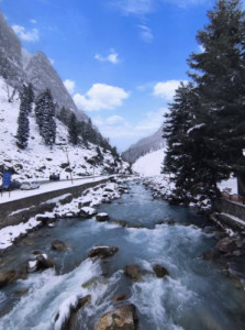 Amidst the snow-covered peaks, the gentle flow of the river in the mountain valley is a sight to behold